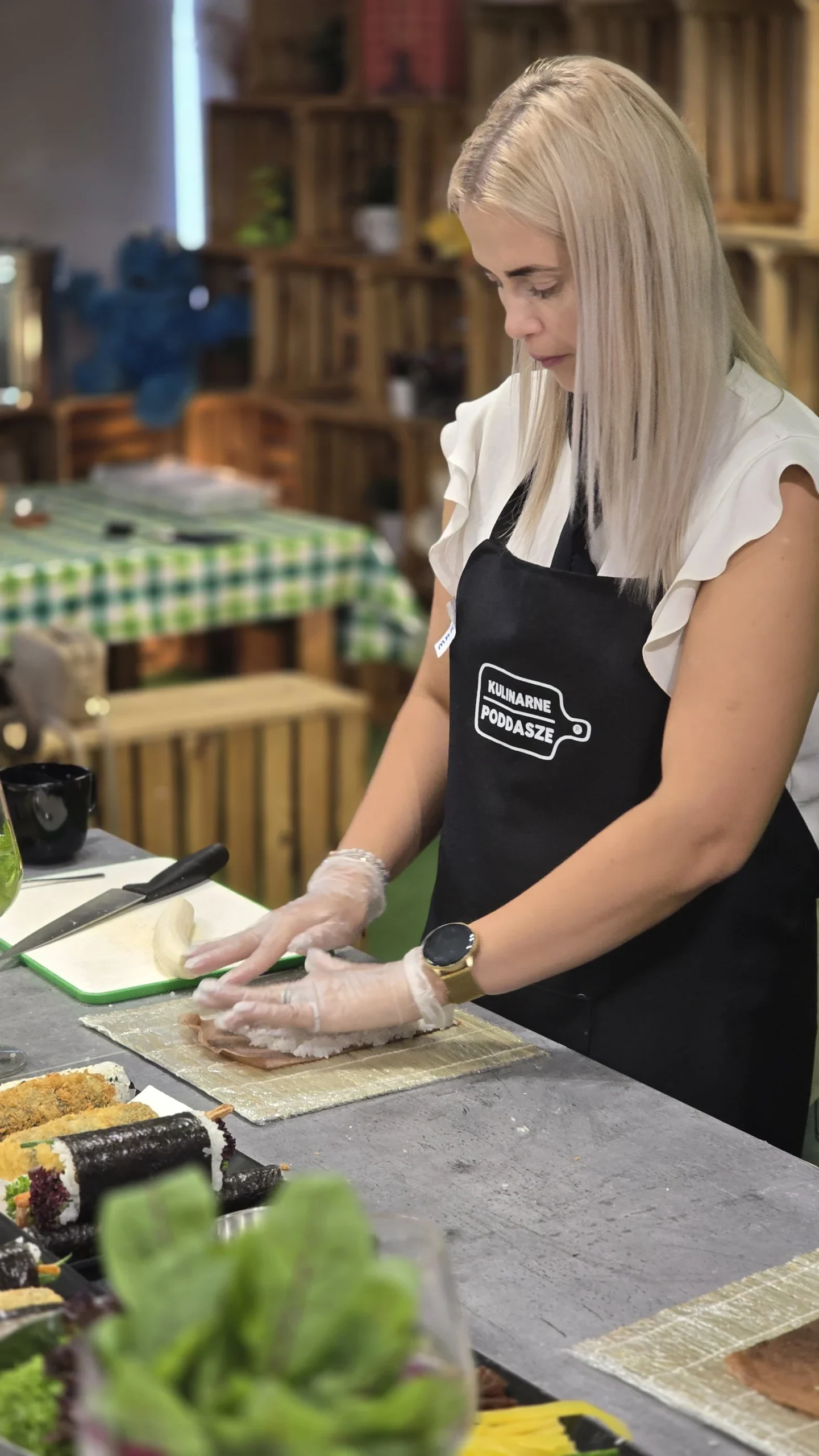 Uczestniczka w fartuchu pracuje przy kuchennym blacie.